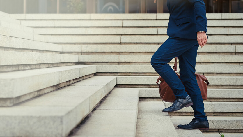 A man in a business suit climbs the steps of a building.