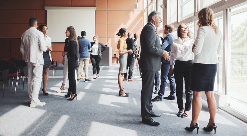 Business men and women network together at a conference